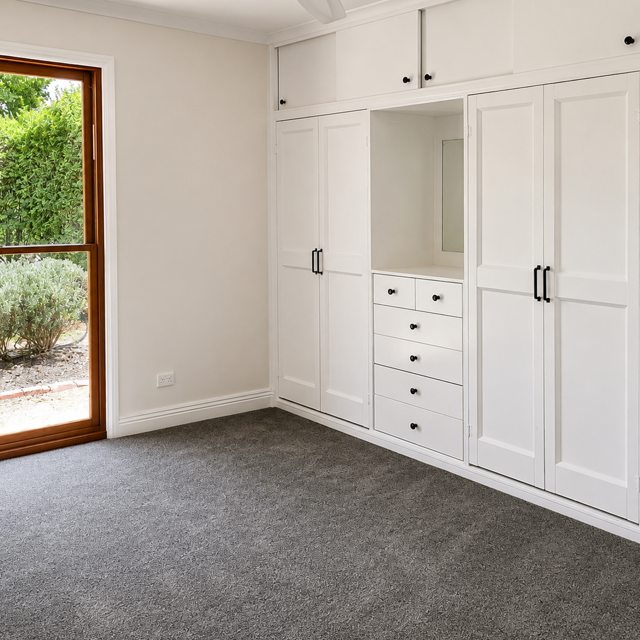 Custom built-in wardrobes with integrated drawers and dressing area in bedroom